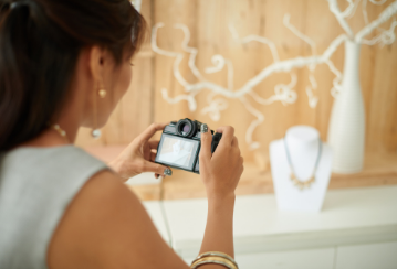 A person takes a photo of a necklace that's placed on a bust.